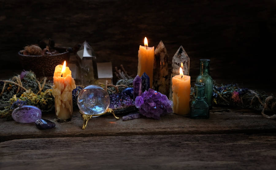Crystals used in Wicca crystal magic with candles against a dark background.