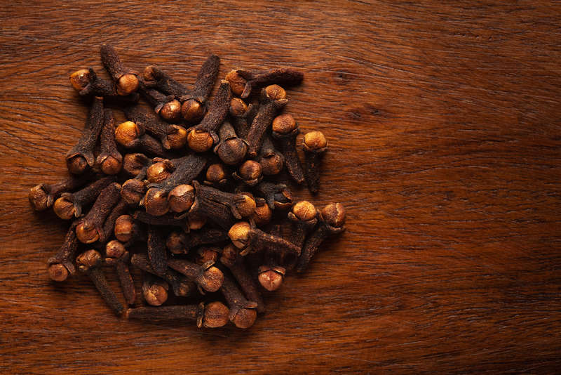 Cloves on a brown table used in herbal magic for their magical properties.