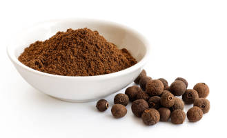 Freshly grinded allspice and allspice balls on a white background.