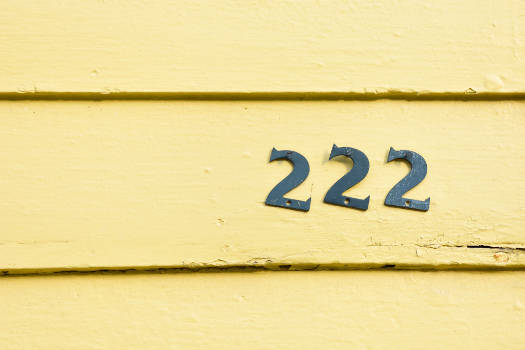 Angel number 222 on a yellow wooden door. 