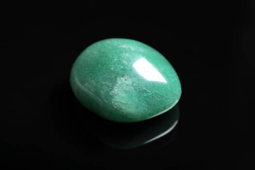 An aventurine gemstone with magical and metaphysical properties on a black background. 