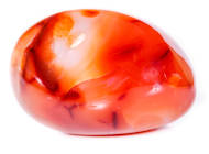 An orange and red carnelian gemstone on a white background.