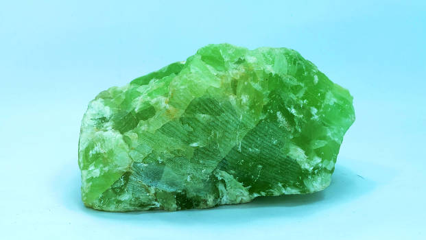 A green jade crystal with magical and metaphysical properties on a light blue background. 