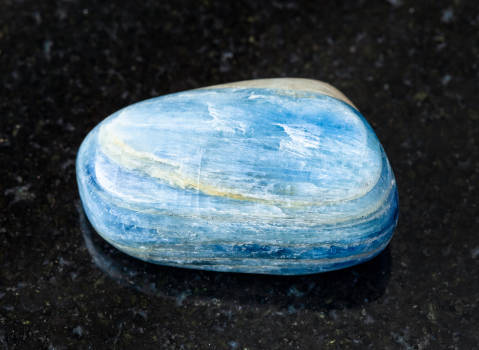 A blue Kyanite crystal with magical and metaphysical properties on black marble. 