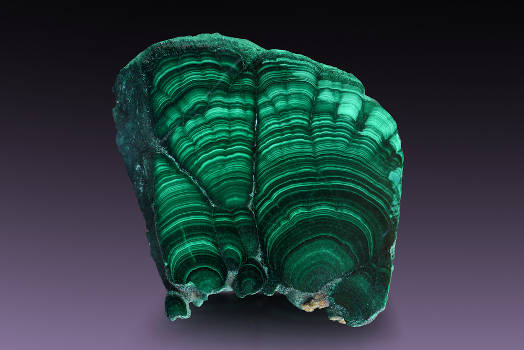 A beautiful green malachite crystal with magical and metaphysical properties on a dark background. 