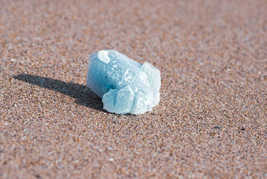 A light blue celestite crystal with magical and metaphysical properties on the sand. 