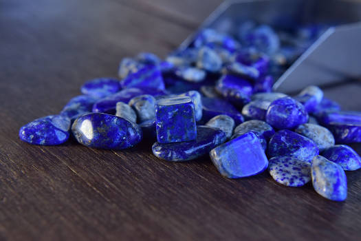A bunch of blue lapis lazuli stones with magical and metaphysical properties on a wooden table. 